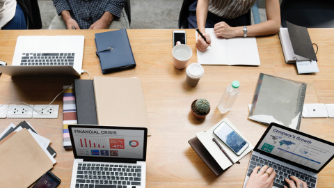 Foto van boven met laptops en handen die schrijven en typen