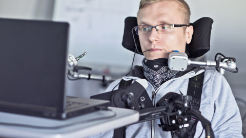 Man in rolstoel voor een laptop