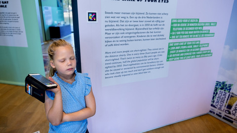 meisje luistert naar gesproken tekst bij bord in museum