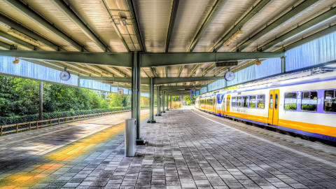 een leeg perron op een treinstation. er rijdt een sprinter voorbij.