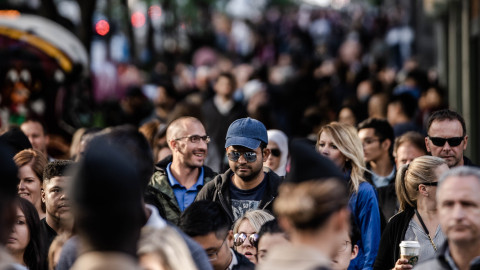 Een straat waarin heel veel mensen lopen die elkaar passeren.