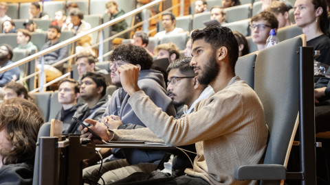 Studenten zitten in een hoorcollegezaal te luisteren naar een spreker