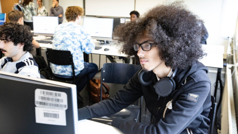 Student zit achter computer in leslokaal