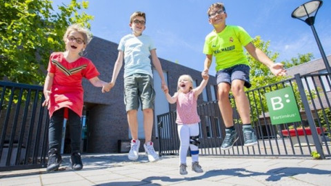twee jongens en twee meisjes springen hand in hand in de lucht