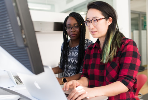 Twee vrouwen werken achter een desktopcomputer aan toegankelijke code