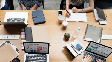 Foto van boven met laptops en handen die schrijven en typen