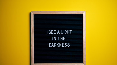 zwart prikbord met witte tekst die luidt 'I see a light in the darkness'