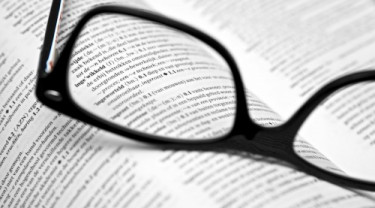 Een bril die op een woordenboek ligt