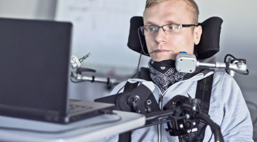 Man in rolstoel voor een laptop