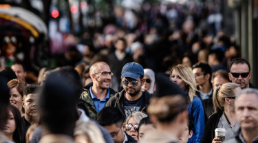 Een straat waarin heel veel mensen lopen die elkaar passeren.