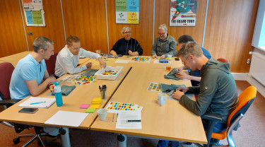 Volwassenen zitten aan tafel en spelen met gekleurde steentjes