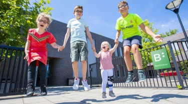 twee jongens en twee meisjes springen hand in hand in de lucht
