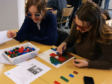 twee jonge vrouwen met bril spelen met lego aan een tafel
