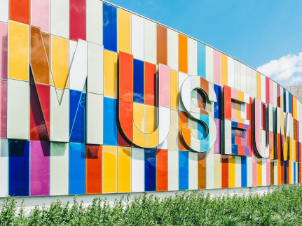 Met kleurrijke vlakken is het woord museum op een gebouw aanbracht