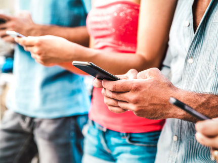 vier mensen op een rij, ze hebben alle vier een mobiel in hun handen