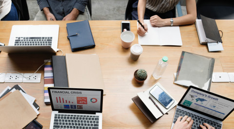 Foto van boven met laptops en handen die schrijven en typen