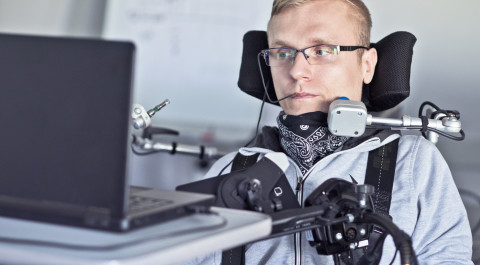 Man in rolstoel voor een laptop