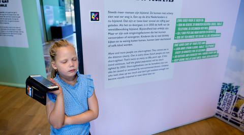 meisje luistert naar gesproken tekst bij bord in museum
