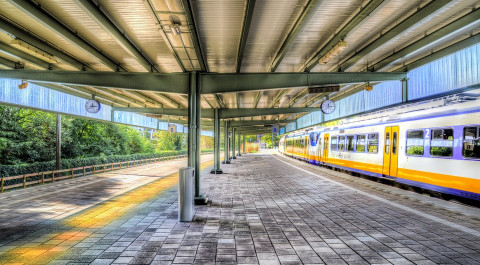 een leeg perron op een treinstation. er rijdt een sprinter voorbij.