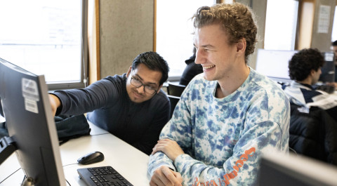 Twee jongens zitten achter een computer en lachen