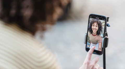 Een vrouw bedient de video-optie op haar mobiel die bevestigd is op een selfiestick.
