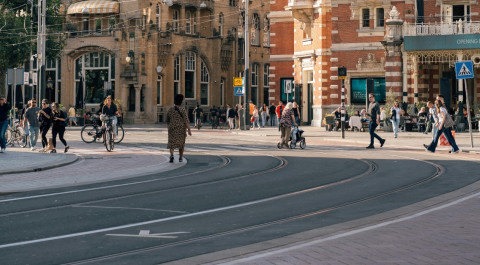 kruispunt in Amsterdam waarop je een tramlijn, fietspad, weg en weggebruikers afbeeld ziet