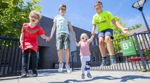 twee jongens en twee meisjes springen hand in hand in de lucht