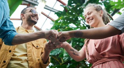 Vier personen steken hun vuisten bij elkaar